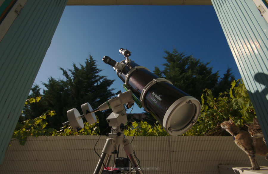 Télescope noir sur une monture blanche, dirigé vers le ciel bleu