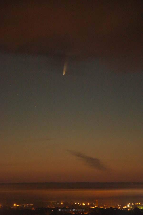 Fond crépusculaire sombre. En bas, paysage nocturne, quelques lueurs urbaines. En haut, nuées noires dues à l'incendie, et la comète juste en dessous