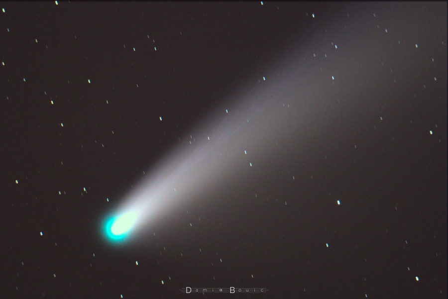 Comète dont la queue s'étire vers le haut à droite, nuances de bleu visibles à l'intérieur et tout le long