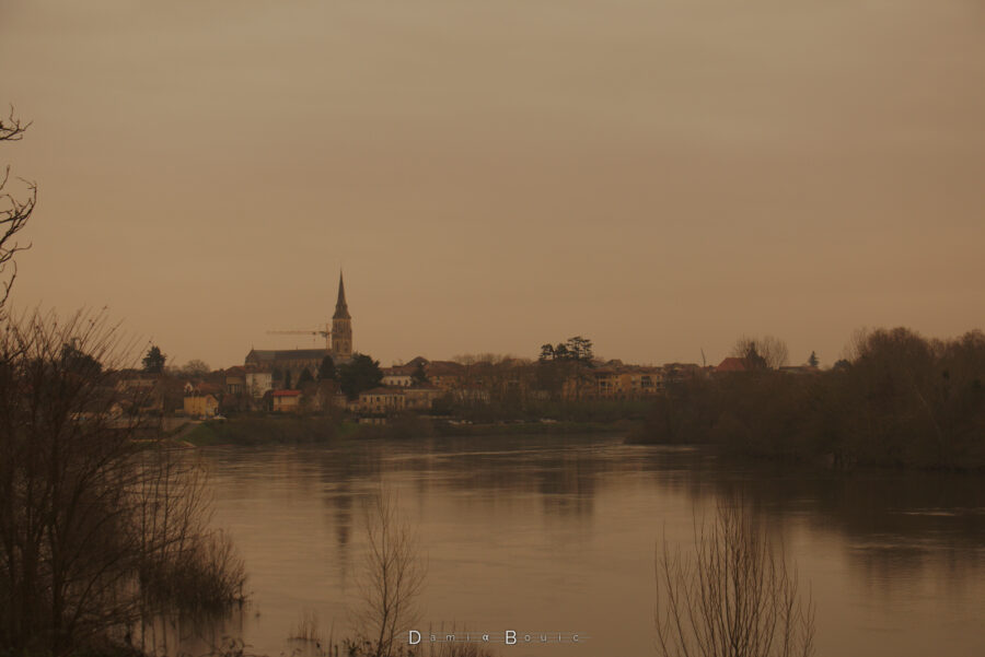 Vue centrée sur Bergerac, au loin, sur la Dordogne, toujours sous ce ciel jaune