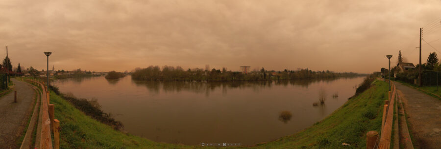 Image panoramique, donc déformée, montrant tout le fleuve Dordogne, qui adopte une allure de large sourire, avec un ciel aux couleurs chaudes