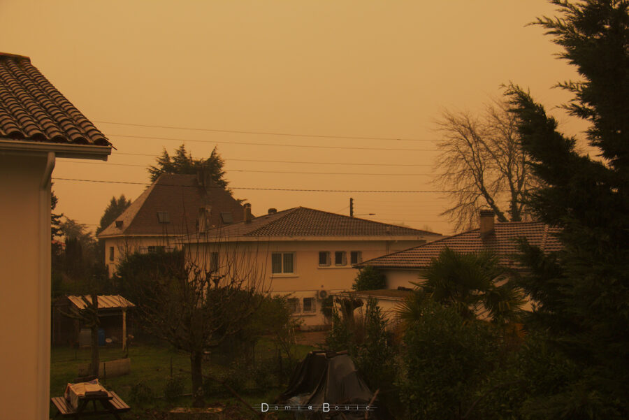 Photo montrant quelques maisons sous un ciel franchement orange