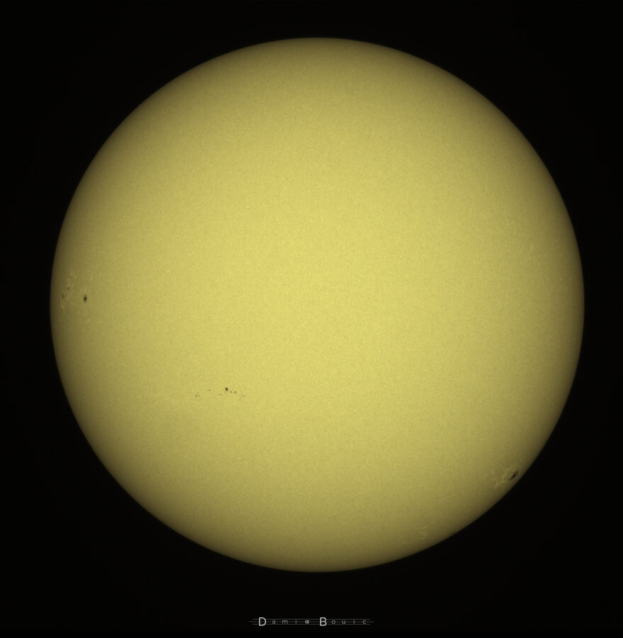 Image du disque solaire montrant plusieurs groupes de taches solaires, disposées de long de l'équateur de l'astre. Le premier groupe est situé à gauche au bord du disque, et consiste en trois tâches solaires, dont la plus grosse est située à droite. Vers le milieu et le bas du disque, une petite grappe allongée de tâches solaire est visible. A droite et vers le bas enfin, une grosse tache solaire. La surface du soleil apparait ici granuleuse.