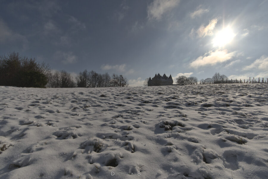 La neige ondule doucement sous le Soleil, et la silhouette sombre du chateau émerge derrière la crête.