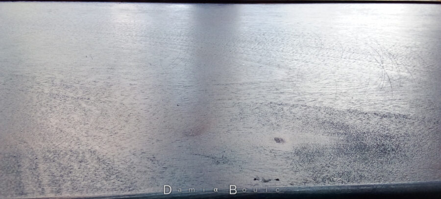 Vue rapprochée de la surface qui met en avant les différentes réflectivités de la surface, soulignant le grain du bois.