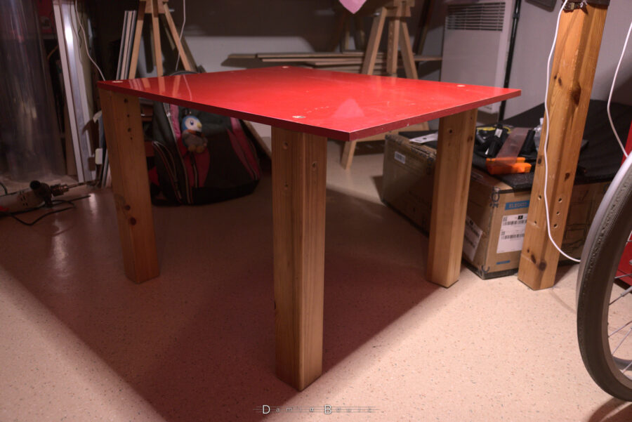 La table qui va accueillir le caisson et l'imprimante 3D, assemblée, posée sur ses 4 pieds, avec un léger déport en avant de la planche rouge