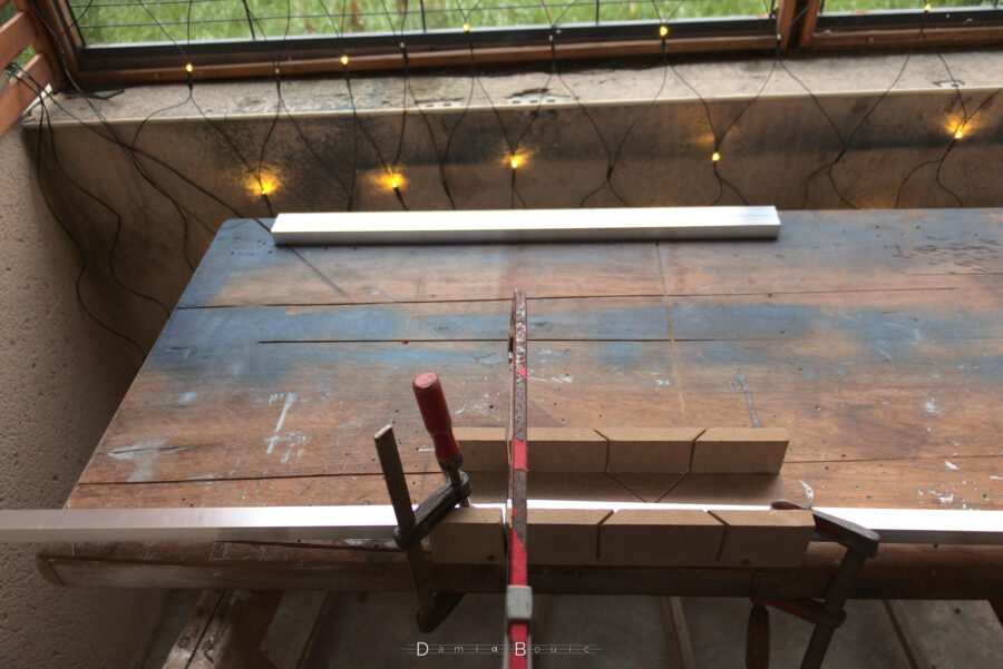 Etabli en bois qui semble avoir bien vécu au vu des traces de peintures et de coupes, qui sert de support au débitage des différentes poutrelles en aluminium. Celles qui sont terminées sont stockées plus loin