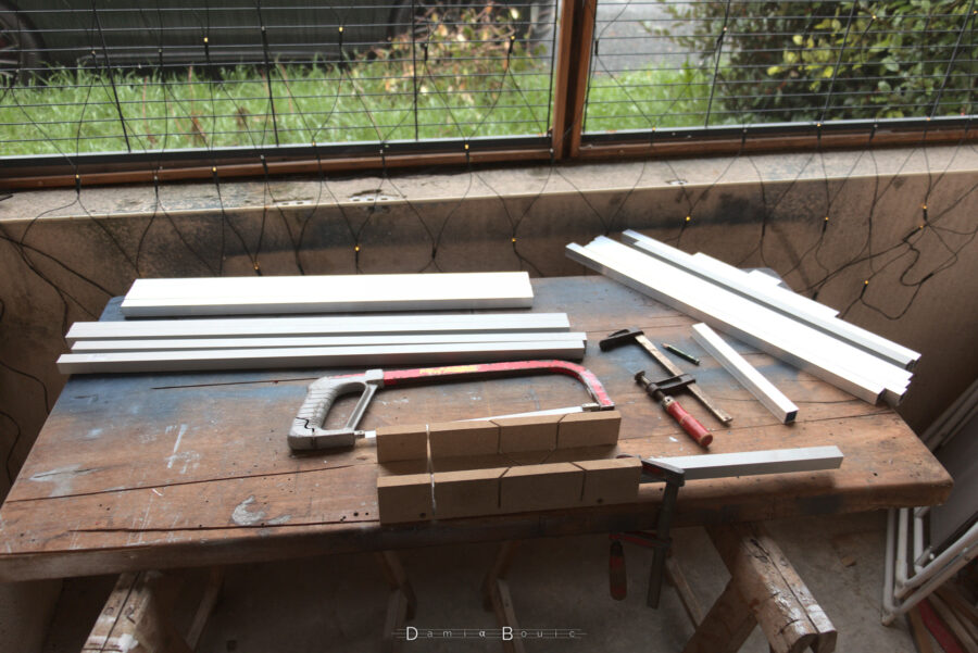 Travail en cours sur l'établi situé sur la terrasse. Les poutrelles coupées sont presque finies. Sur la partie droite de la planche sont disposées les chutes.