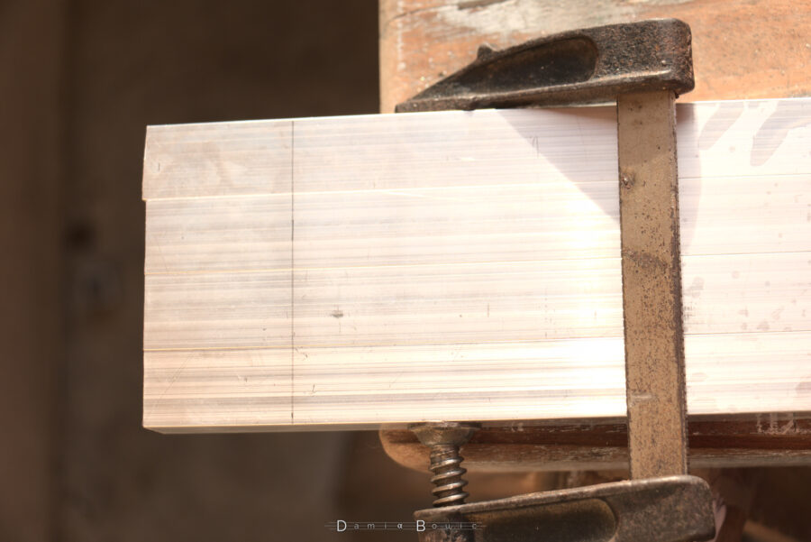 Rectification des longueurs des barres d'alu, avec le trait de coupe placé cette fois-ci correctement, 4 barres sont tenues par un serre-joint