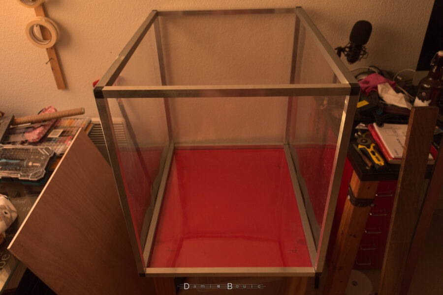 Le caisson est posé sur la table rouge, avec toutes les faces, sauf celle du dessus et du devant, couverte de panneaux en plastique