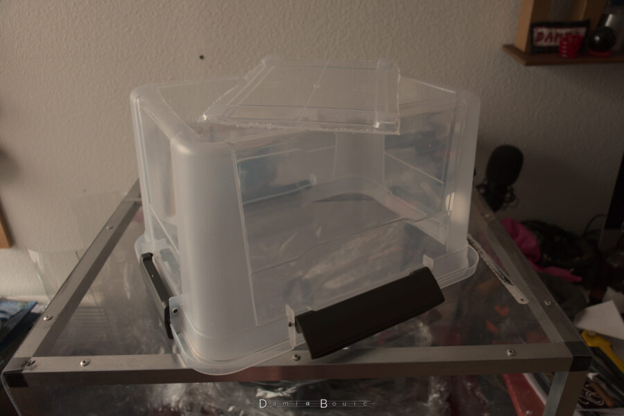 Une boite en plastique, retournée, dont le fond a été découpé, dans la douleur visiblement car les bords sont peu réguliers et garnis de débris plastiques