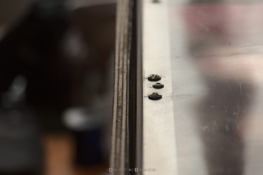 Détail sur le haut du caisson, la jointure est hermétique entre la porte et la barre en alu. Deux boulons sont visibles de part et d'autre d'un rivet.