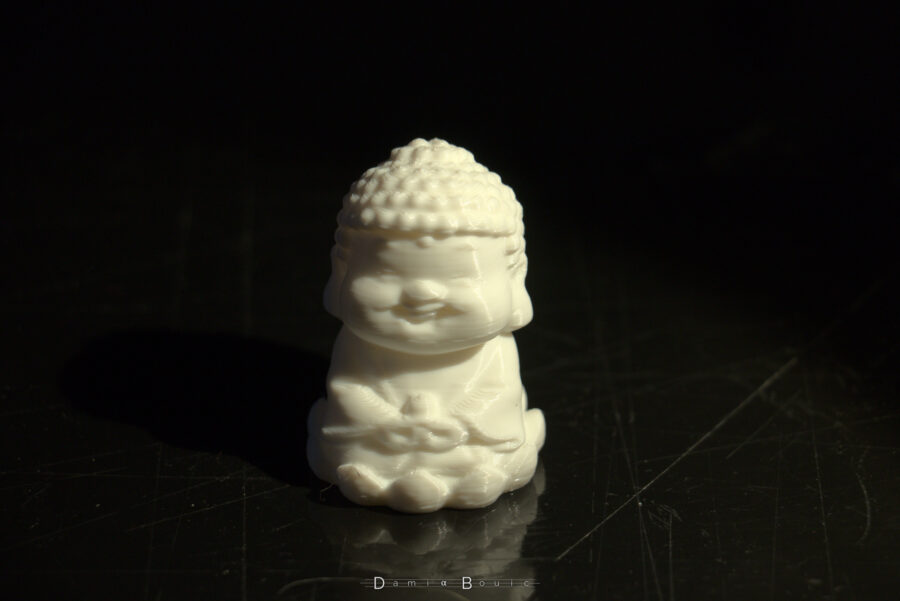 Petite figurine en plastique à l'effigie de Buddha, souriant. Les couches de filament sont presque invisibles tellement elles sont fines