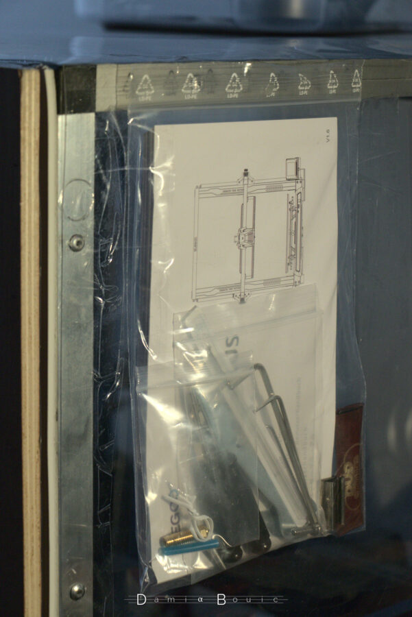 Dans une poche en plastique collée contre le caisson sont disposés le manuel d'utilisation et les divers outils qui peuvent être utiles à servicer l'imprimante