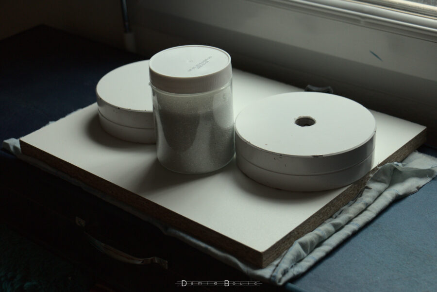 Le cadre a été collé, il est maintenant sous presse avec du tissu, une planche de bois aggloméré mélaminé blanc, mes deux contrepoids de télescope et un pot rempli de petites billes de verre