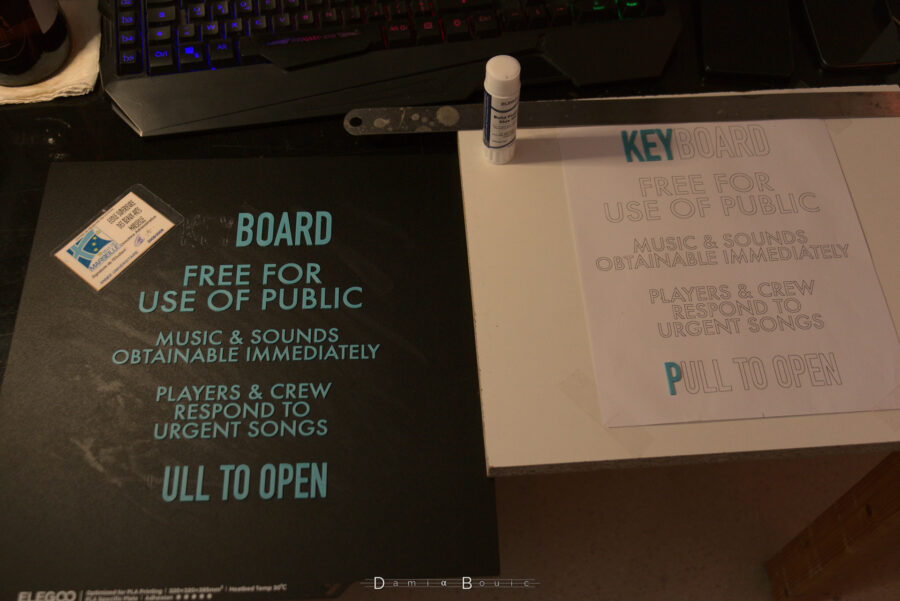 Première procédure de transfert. A gauche le support amovible de l'imprimante 3D avec le texte qui est défait petit à petit, à droite, les lettres qui sont collées sur le papier imprimé, pour retrouve l'exacte disposition du lettrage, collé à la colle en bâton style école primaire.