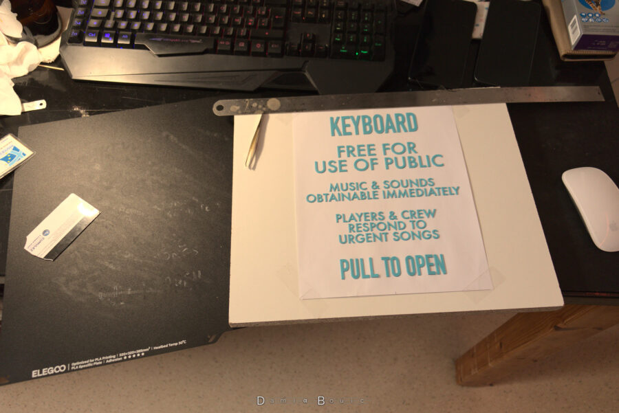 La procédure finie, les texte en lettre plastique est désormais sur la feuille de papier, scotchée à une planche de bois. A gauche, la plaque d'impression vide, mais salie par la colle