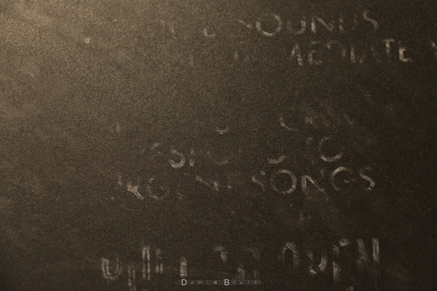 Esthétique de lettres fantomatiques à semi-effacées sur la plaque d'impression granuleuse, certains mots sont lisibles comme SONGS.