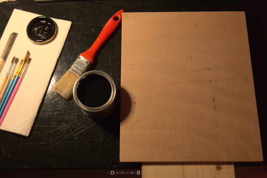 Au tour de la plaque de recevoir la peinture. Noire sur le coup. Celle-ci est disposée à droite, à sa gauche le pot de peinture ouvert et un pinceau plat de taille 30