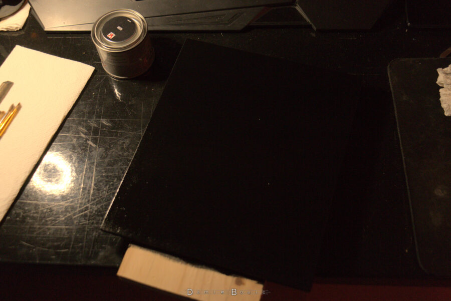 La plaque a été peinte et se confond littéralement avec mon bureau d'aspect noir et brillant. Le pot de peinture noire a été refermé