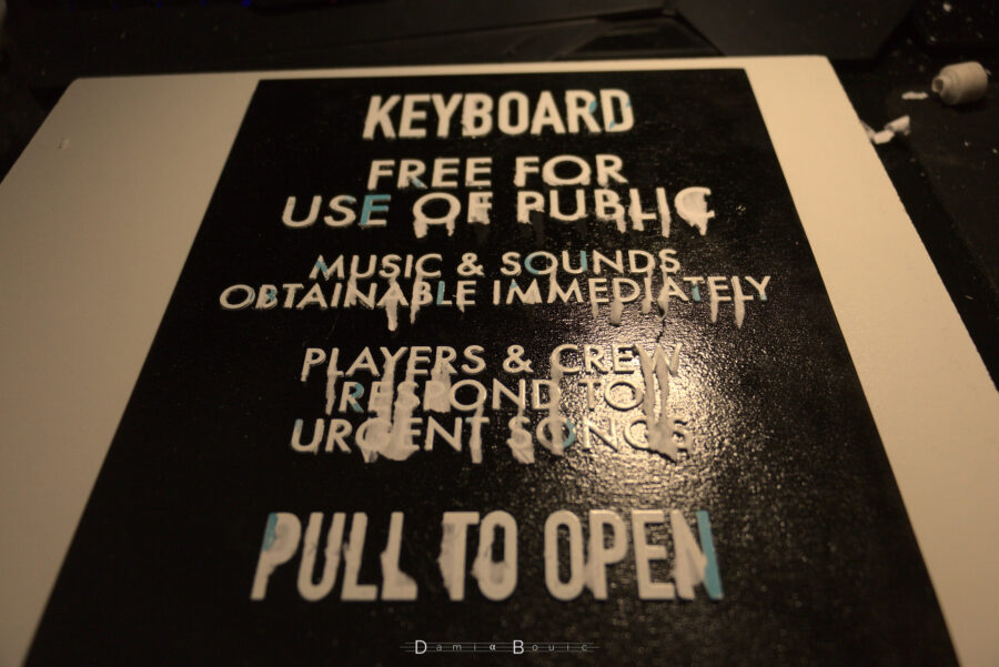 Le papier a été totalement retiré, montrant un texte peu propre avec pas mal de bandelettes de papier qui sont restées collées au lettrage. Certaines lettres aussi on perdu leur peinture blanche.