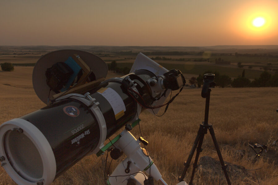 Mon poste de travail, avec boitier 70D au foyer du télescope, 400D en parallèle (recouvert d'un chapeau) et le trépied photo, vide car c'est l 450D qui prends cette vue, où tout pointe vers un Soleil bas sur l'horizon, qui prends des teintes cuivrées dans un ciel rougeoyant