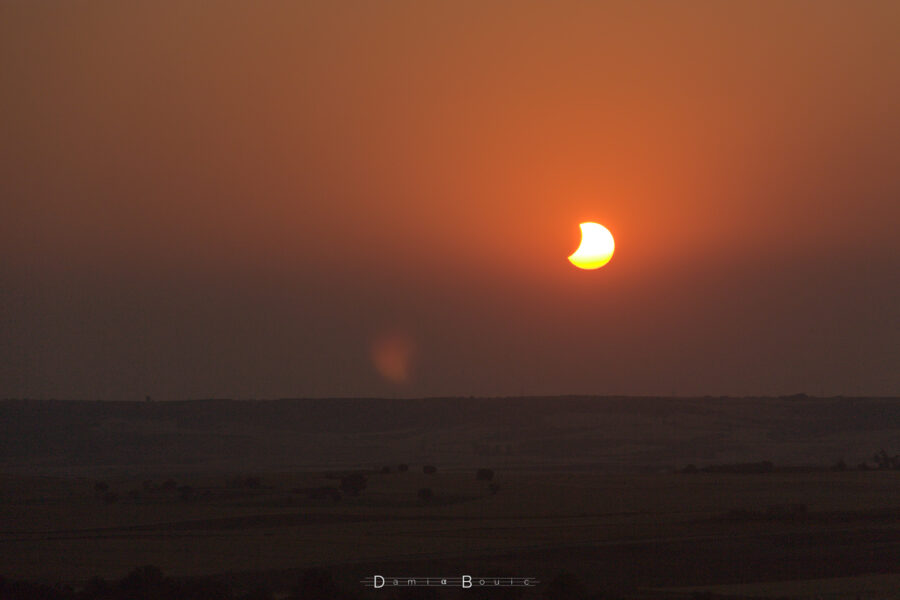 Le Soleil se couche encore échancré par la Lune. Il est encore au dessus de l'horizon, mais plus pour longtemps.